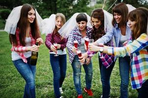 Sechs Mädchen in karierten Hemden trinken Champagner auf dem Junggesellinnenabschied. Gruppe glücklicher Mädchen. foto
