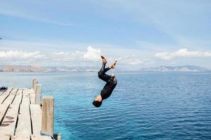 Ein Mann macht einen Rückwärtssalto ins Wasser foto