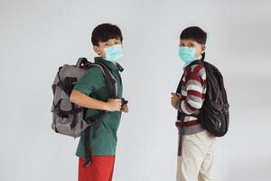 Zwei asiatische Schuljungen in medizinischen Masken posieren zusammen foto