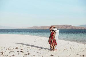 Zwei Frauen im Sommerhut machen mit ihrer Hand am weißen Sandstrand ein Herz foto