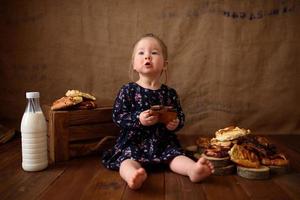 kleines Mädchen in der Küche isst süßes Gebäck. foto