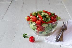 Salat auf weißem Holzhintergrund aus Tomaten, Gurken, Salat und Paprika. Konzept für gesunde Ernährung. foto