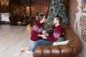 ehemann und frau in identischen strickpullovern haben spaß zusammen, um weihnachten zu feiern. foto