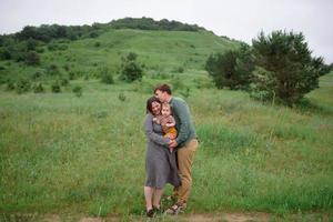 Mama, Papa und Tochter. eltern halten baby an den händen und gehen auf die kamera zu. foto