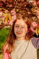 Frühlingsporträt eines Mädchens. Teenager-Mädchen auf einem Hintergrund von blühender Sakura. foto