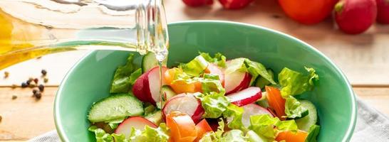 Salat aus frischem Gemüse mit Olivenöl in Keramikschale auf Holzhintergrund. foto