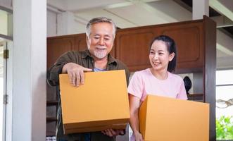 Umzugstagskonzepte, asiatische Familie, die Kisten in ein neues Zuhause trägt, glückliche Tochter im mittleren Alter und älterer Vater im neuen Haus
