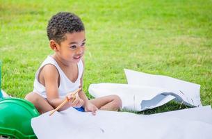 porträt eines glücklichen afroamerikanischen kinderjungen, der draußen in einem park spielt, ein kind, das bauarbeiterkonzepte spielt foto