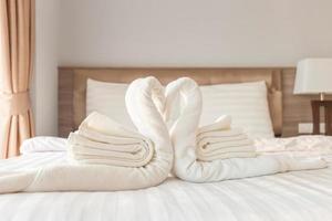 Handtuch in Schwanenform auf Bettlaken im Schlafzimmer gefaltet foto