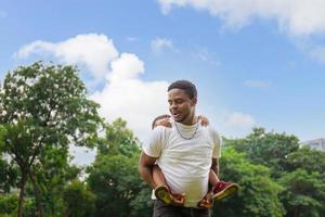 fröhlicher afroamerikanischer vater und zwei söhne spielen im park, glücksfamilienkonzepte, eltern und kinder spielen im park foto