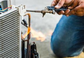 nahaufnahme der reparatur der klimaanlage verwenden sie brenngase und sauerstoff zum schweißen oder schneiden von metallen, autogenschweißen und autogenschneiden, handwerker auf der bodenbefestigung der klimaanlage foto