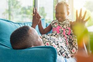 fröhlicher afroamerikanischer vater und tochter spielen im wohnzimmer, glücksfamilienkonzept foto