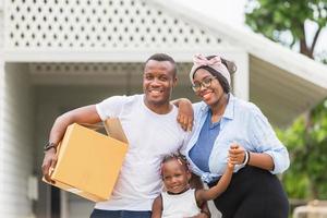 Fröhliche afroamerikanische Familie mit Gepäck und Kisten ins neue Zuhause tragen, Glücksfamilie am Umzugstag foto