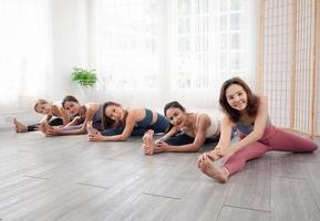 Drei attraktive schöne asiatische Frauen mit ihren Trainern üben die Pose während ihres Yoga-Kurses in einem Fitnessstudio. Zwei Frauen praktizieren gemeinsam Yoga. foto