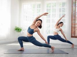Zwei attraktive schöne asiatische Frauen üben die Pose während ihres Yoga-Kurses in einem Fitnessstudio. Zwei Frauen praktizieren gemeinsam Yoga. foto