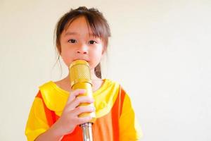 schönes baby trägt ein gelb-orangees outfit, gokowa-outfit oder mugunghwa, und hält goldenes mikrofon, das musik singt. Modekleid für Mädchen und Teenager. foto