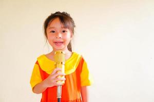 schönes baby trägt ein gelb-orangees outfit, gokowa-outfit oder mugunghwa, und hält goldenes mikrofon, das musik singt. Modekleid für Mädchen und Teenager. foto