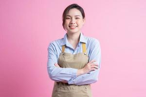 junge asiatische kellnerin, die auf rosa hintergrund steht foto