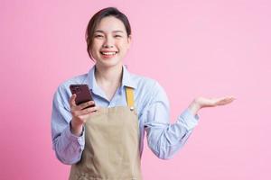 junge asiatische kellnerin, die auf rosa hintergrund steht foto