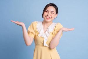 junge asiatische frau, die auf blauem hintergrund aufwirft foto