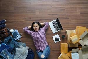 draufsicht kleine geschäftsinhaberin, die auf holzboden mit postpaket, online-verkauf, e-commerce, versandideenkonzept liegt foto