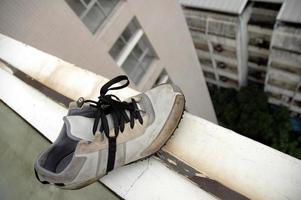 Trauriger übrig gebliebener Schuh am Rand eines Gebäudedachs foto