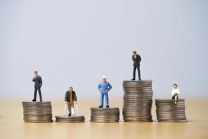 Fünf Miniaturfiguren in jeder Karriere stehen zu unterschiedlich hohen und niedrigen Münzen, die für eine Variation des Einkommens oder Gehalts in jedem Jobkonzept gestapelt werden. foto