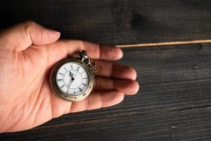 Männerhände halten eine Taschenuhr und einen schwarzen Hintergrund. foto