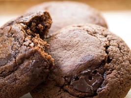 hausgemachte weiche dunkle Schokoladen-Brownie-Kekse auf einem Holzteller. Nahaufnahme Kekse werden gebissen. sehen gut und lecker aus. foto