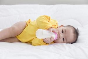 ein asiatisches baby schläft auf dem bett und saugt die abgefüllte milch. foto