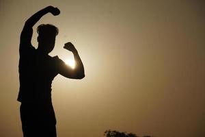 Silhouettenbild des Mannes mit frei fallender Sonne - Motivationskonzept foto