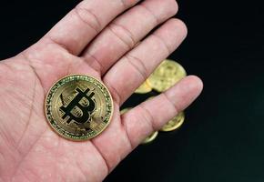 Bitcoin-Münze auf der Hand auf schwarzem Hintergrund platziert foto