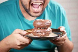 junger Mann isst Donut, selektiver Fokus foto