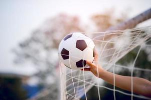 das zugeschnittene Bild von Sportlern, die den Ball und das Fußballfeld fangen. Sport-Image-Konzept. foto