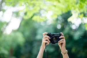 Fotograf und Kameraliebhaber schwarze Kamera und natürlicher grüner Hintergrund foto