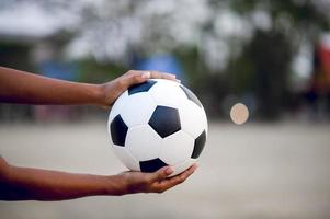 das zugeschnittene Bild von Sportlern, die den Ball und das Fußballfeld fangen. Sport-Image-Konzept. foto