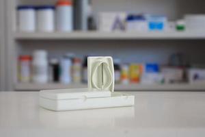 tablettenschneider mit unscharfen regalen von medikamenten im hintergrund der apotheke drogerie foto