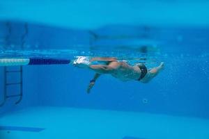 kaukasischer sportler, der im schwimmbad unter wasser schwimmt foto