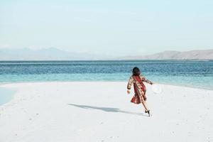 glückliche Frau läuft und tanzt am weißen Sandstrand foto