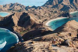 Landschaftsansicht von der Spitze der Insel Padar in Labuan Bajo mit Touristen, die den Hügel hinuntergehen foto