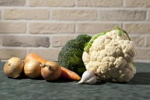 Zwiebeln, Blumenkohl, Karotten für Essen, Kürbis, Gurke und Blumenkohl für Salat auf einem braunen Tisch, auf einem schönen Hintergrund, foto