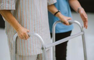 Nahaufnahme eines jungen Physiotherapeuten, der älteren Patienten bei der Verwendung von Rollatoren während der Rehabilitation hilft foto