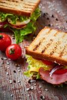 Sandwich mit Salat und Schinken auf einem hölzernen Hintergrund foto