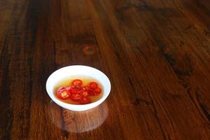 Chili und Fischsauce in kleinen weißen Tassen auf einem Holztisch im Restaurant. foto