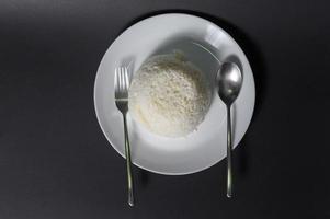 Reis auf weißer Platte über schwarzem Hintergrundstudio foto