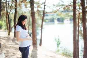 schwangere frau, die ihre hände auf bauch hält foto