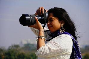 weibliches Fotografenbild Porträt eines Fotografen, der ihr Gesicht mit der Kamera bedeckt. foto