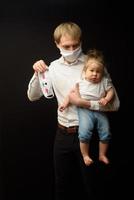 Vater in einer medizinischen Maske hält seine kleine Tochter. das Konzept des Schutzes von Kindern während der Coronavirus-Epidemie foto