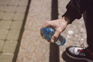 Hand, die eine Flasche Wasser hält foto