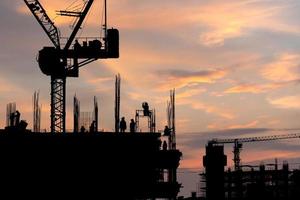 Silhouette des Arbeiterteams auf der Baustelle, Baustelle bei Sonnenuntergang am Abend foto